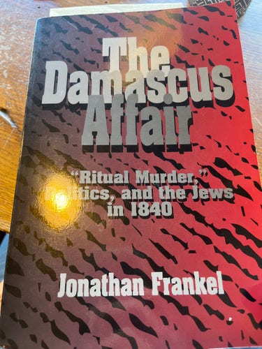 Cover of a book titled "The Damascus Affair: Ritual Murder, Politics, and the Jews in 1840" by Jonathan Frankel, featuring a color gradient of dark brown to red with camouflage-like patterns.