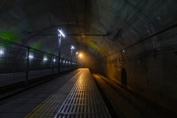 A photograph of one of the platforms of Doai station. It is 70metres below ground. It appers gloomy with dim light and raw concrete walls.