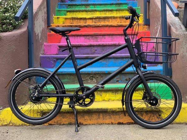 A black bike in front of stairs with rainbow-colored steps.