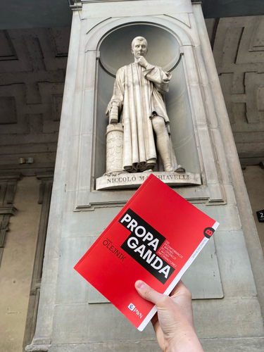 Książka propaganda. W tle i pomnik Niccolo Machiavellego