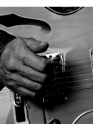 Photo N&B Photo d'une main sur jouant sur les cordes d'une guitare. 