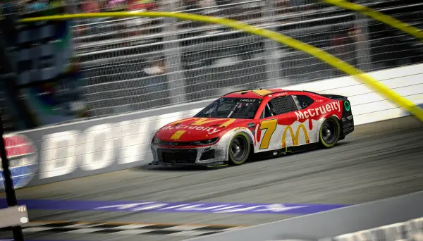 Simulated NASCAR stock car on track. McCruelty the primary sponsor, imitating the traditional McDonald's logo. Paint scheme is a white base with red paint dripping down from the top, loosely resembling blood. 