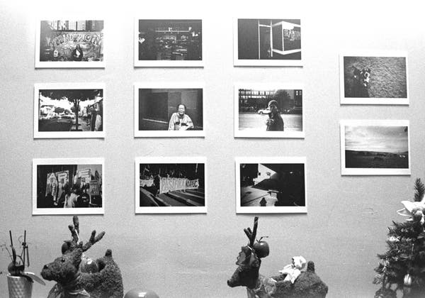 a scan of a black and white photo showing some photos printed and pasted on a wall, like a small photo exhibition