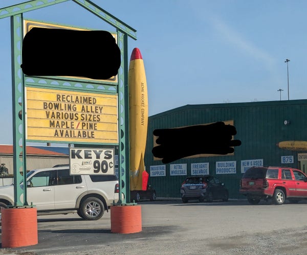 A  yellow sign advertising "reclaimed bowling alley; various sizes; maple/pine available"
