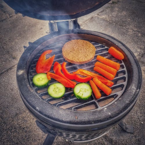 Bell pepper, carrot, cucumber and a veggie burger on the cast iron grill plate