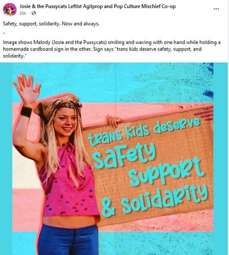 Image shows Melody (Josie and the Pussycats) smiling and waving with one hand while holding a homemade cardboard sign in the other. Sign says “trans kids deserve safety, support, and solidarity.”