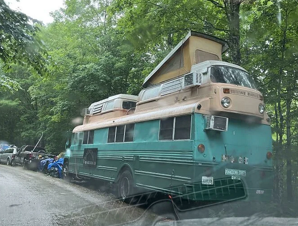 An older bus with two VW buses (or at least the top parts) incorporated in it's roof.
