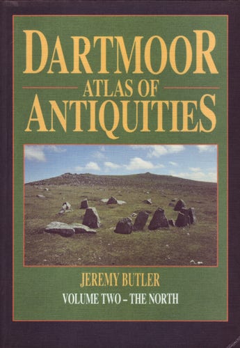 The front cover of the 'Dartmoor Atlas of Antiquities: Volume 2 - The North' by Jeremy Butler. Green with title in yellow and a colour photo of the Nine Stones Cairn Circle at Belstone near Okehampton in Devon.