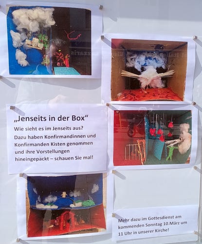 Schaukasten einer Kirchengemeinde mit Fotos vom Konfirmand*innen-Bastelprojekt „Jenseits in der Box – wie sieht es im Jenseits aus?“. Die Kinder haben in Pappkisten ihre Vorstellung von Himmel und Hölle umgesetzt.
