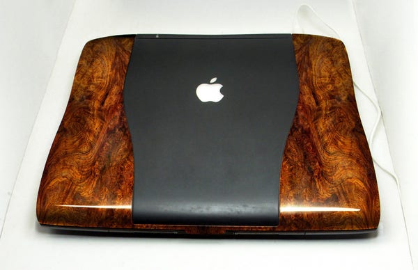A photo of a PowerBook G3, and the top case is a tasteful walnut burl. Like so seriously tasteful you can taste it. The centre section is black rubberised, while the outside is a deep warm polished wood you just want to touch. But not too much cos damn it'd pick up the fingerprints.