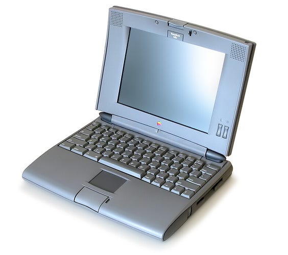 A promo looking photo of an Apple PowerBook 540c. The laptop is pictured grey with a tiny rainbow apple logo, against a white background, and opened with the screen off.