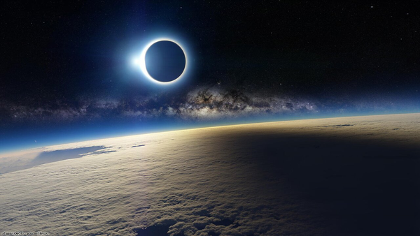 A dark circle surrounded by a bright ring –the Sun eclipsed by the Moon– overs over the Earth in space, casting a shadow on it. A starry band crosses the black sky horizontally, between the eclipsed Sun and the Earth.
