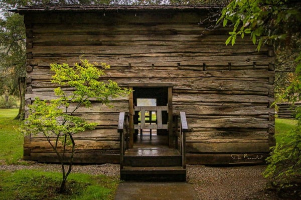 A photograph of a historic wooden Appalachian cabin with a see-through corridor, set against a backdrop of lush greenery on the Blue Ridge Parkway in Virginia. Image at:  https://beautifulsunphotography.com/featured/appalachian-cabin-at-mabry-mill-deb-beausoleil.html See more art & blog at: https://beautifulsunphotography.com/ https://debbeautifulsunphotography.com/ https://www.zazzle.com/store/beautifulsun_designs https://debbeausoleil.com