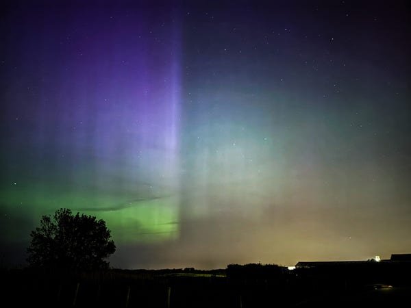 An auroral curtain splitting the picture, bright purple descending to green on the left, fainter green to the right.