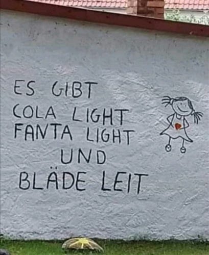 Auf einer weißen Mauer steht:
Es gibt Cola light, Fanta light und Bläde Leit. 

Daneben eine weibliche Strichfigur mit Zöpfen und einem roten herz in den Händen 