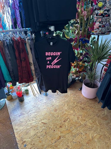 Black T shirt that says Beggin’ for a pegging’ in pink font