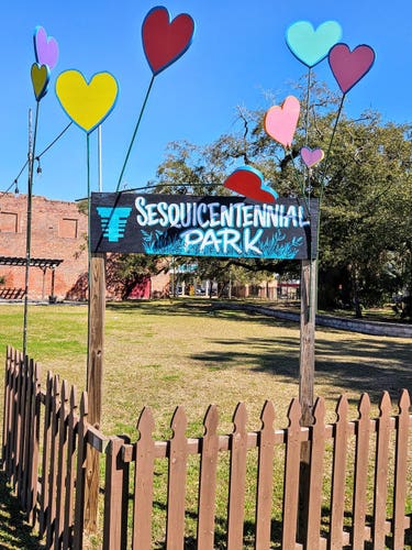 A small park on North Main Street in the Springfield neighborhood, with a modest wooden picket fence and banner sign with fake balloons.