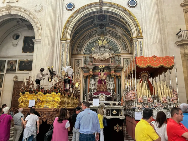Various Holy Week floats on display in Granada Cathedral, people milling about checking out all the glorious details in gold, wood, flowers, candles, silver, etc.  