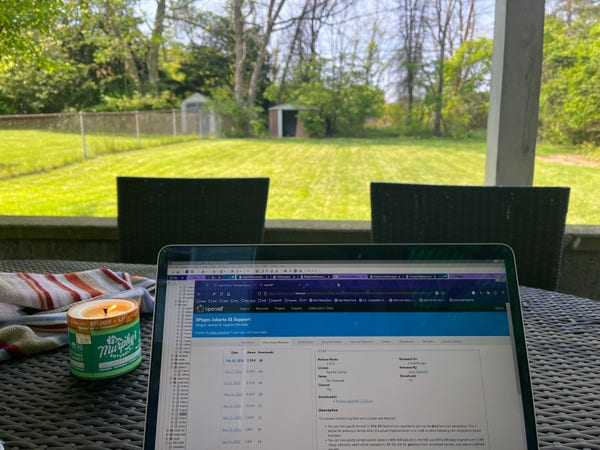 Photo with a laptop in the foreground and a suburban lawn in the background 