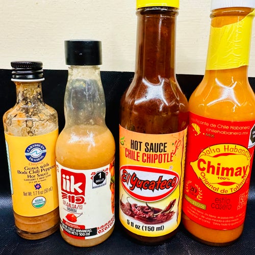 A bunch of four types of hot sauces in a lineup 