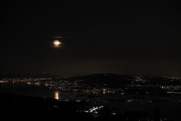 A crescent moon over Lake Zürich, reflecting in the lake.