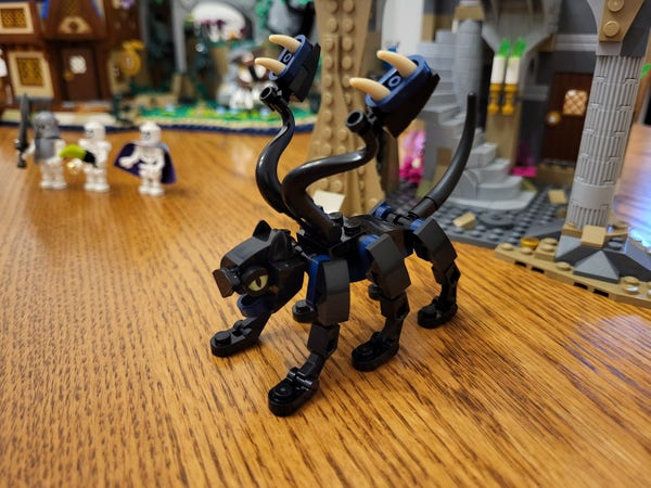 Bag 17 of the Lego Dungeons & Dragons set, consisting just of a brick-built Displacer Beast. It's mostly black, with some dark blue pieces. It's vaguely feline in form, but with six legs, and two extra appendages on its back ending in toothy pads. It has a long tail in the back, and a feline head with yellow eyes and an open jaw.