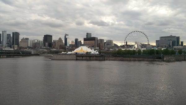 A skyline view of Montréal's old port from across the bay, with the ferris wheel visible in an overcast sunset