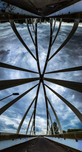 A vertical panorama of the Balibrug bike bridge over the A12 at Zoetermeer. There are numerous struts in the shot and the sky beyond is very cloudy. My bike is in the top left corner.