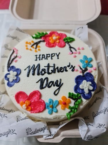 Round cake with white buttercream frosting, painted flowers and Happy Mother's Day greeting