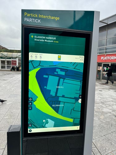A large outdoor touchscreen at Partick Interchange; it shows an interactive map, a weather forecast, date/time and regular old wayfinding sign info