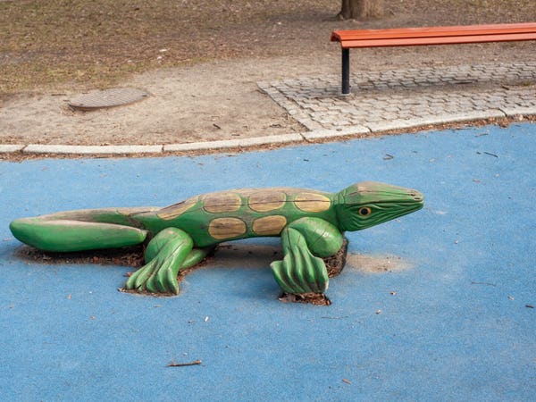 A wooden lizard in a playground.