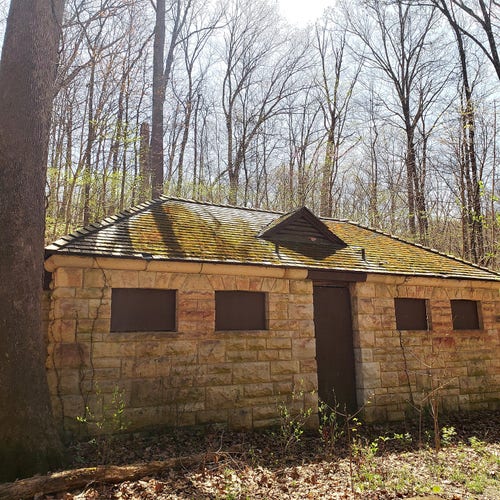 This is an abandoned stone building with boarded up doors and windows in the woods 