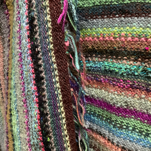 The inside of a multi coloured striped sweater showing loose ends