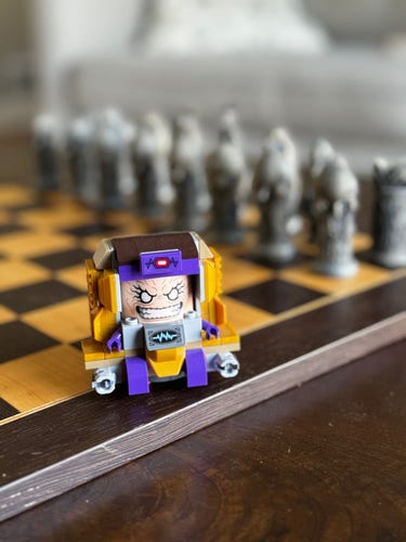 lego modok sitting on chess board