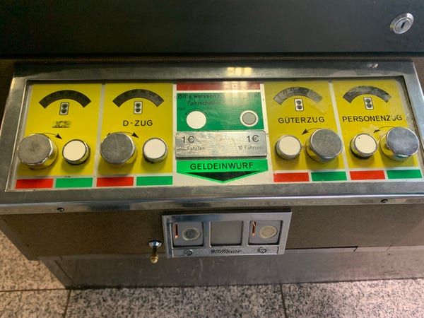 Coin-operated machine with buttons labeled 'ICE’, 'D-ZUG', 'GÜTERZUG', and 'PERSONENZÜG', and a coin slot with a sign for 1 Euro.