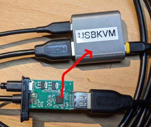 Circuit board from a VGA to HDMI converter next to a USBKVM, with a poorly draw red arrow pointing from the main IC on the converter to the USBKVM.