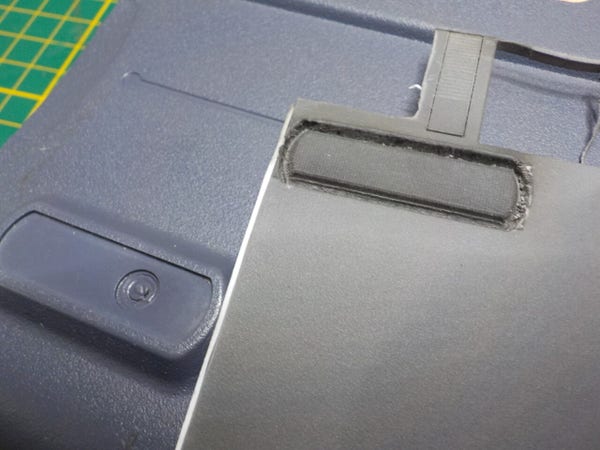 Some grey rubber like sheet with a form cut into it, over the bottom of a Sony laptop with the rubber foot missing.