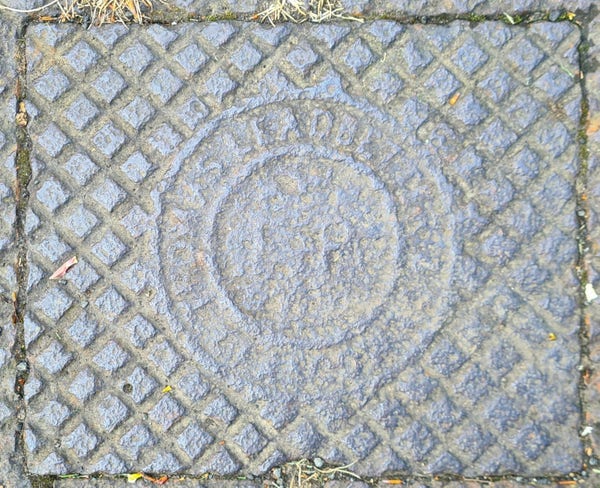 A heavily worn Fire Point Access cover with the words Thomas Leadbetter and Co Glasgow on it.
