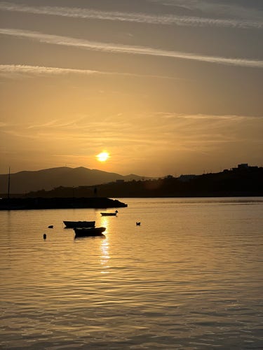 A beautiful golden sky as the sun sets over the Alyki bay this evening. Some small fishing boats in the calm water.
