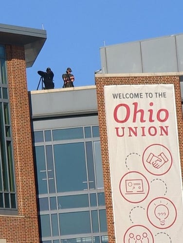 A picture of the Ohio Union building with two snipers standing on the roof.