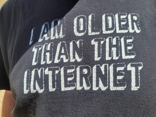 T-shirt that reads "I am older than.l the Internet", white outline words on gray tshirt