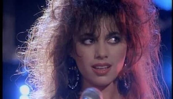 1986 Susanna Hoffs des Bangles, une coiffure en pétard typique des années 80 regarde de côté en chantant dans un micro