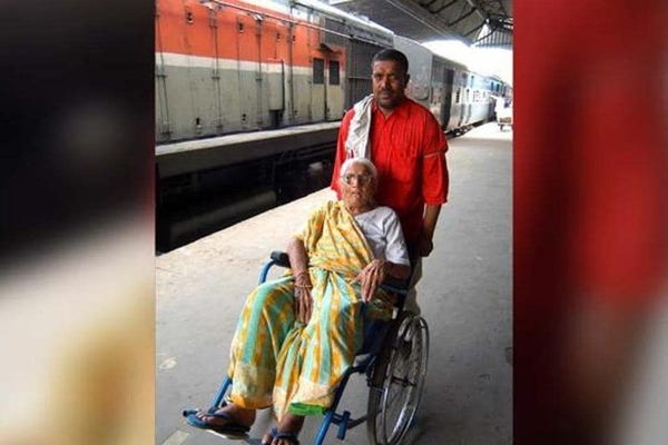 photo of a woman in a wheelchair with a man behind her, helping. They are on a train platform