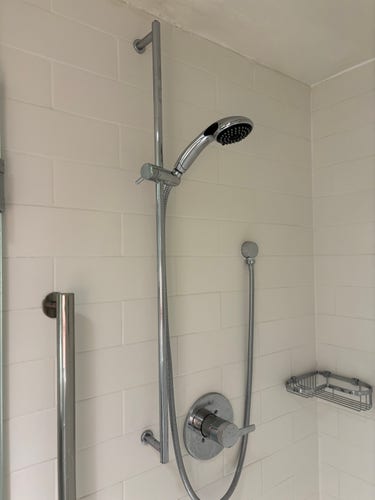 A shower head mounted on a vertical pipe, so it can be slid up and down.