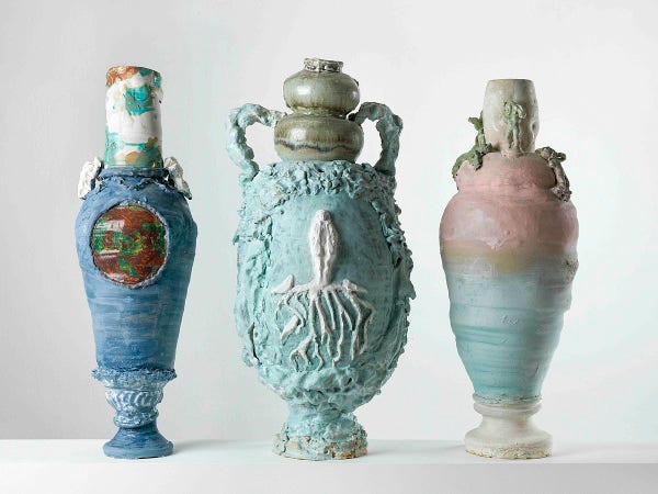 Three ceramic urn-like vessels with textured exteriors and curved lids and bases
