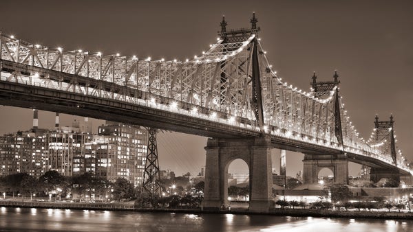 A large cantilever bridge, at night. The bridge is illuminated by lights along the top of the cantilever structure.