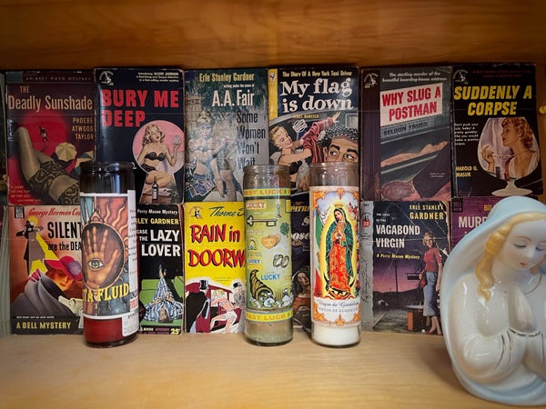 A display pulpy vintage novels and a couple kitschy glass pray candles 