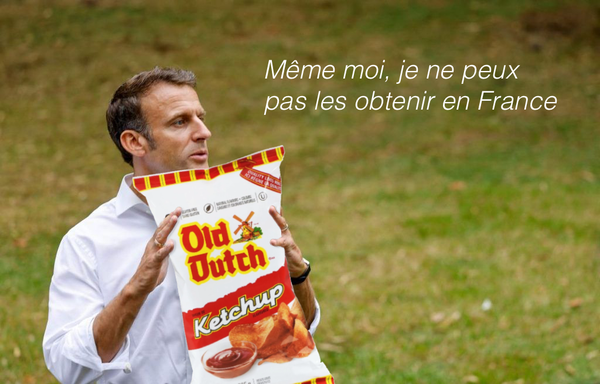 Emmanuel Macron holding a bag of Old Dutch ketchup chips. Caption says, in French: Même moi, je ne peux pas les obtenir en France
