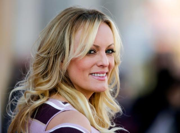 Porn star Stormy Daniels, who spanked Trump with a rolled up copy of Forbes Magazine as a prelude to the subsequent  mushroom harvest that Trump engineered while his 8th wife Malaria was pregnant with his child, looks at the camera with a mischievous smile.