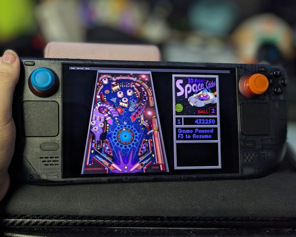 a Steam Deck being held on a desk playing 3D Pinball Space Cadet